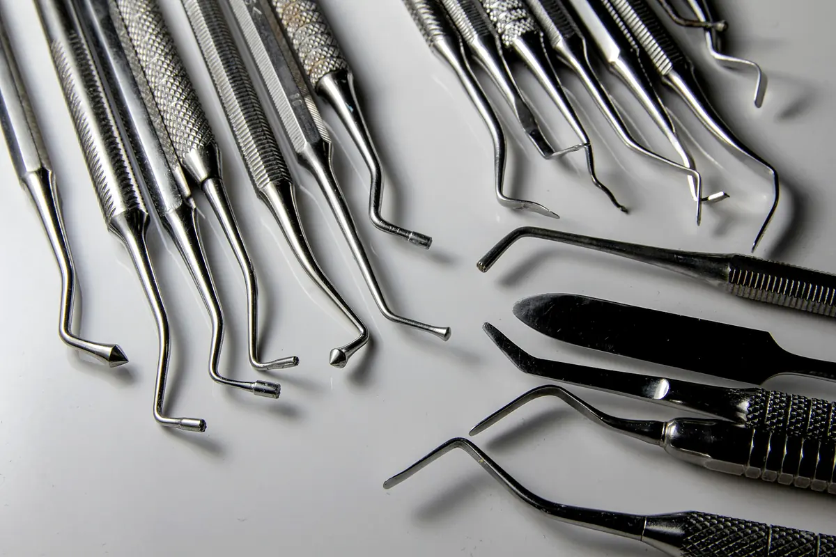 Stainless dental and surgical hand instruments laid out on a light surface