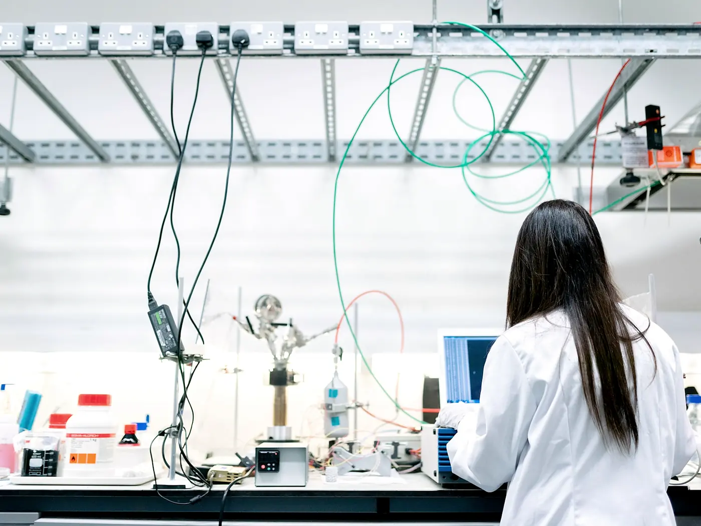 A technician in a white coat working at a long laboratory bench