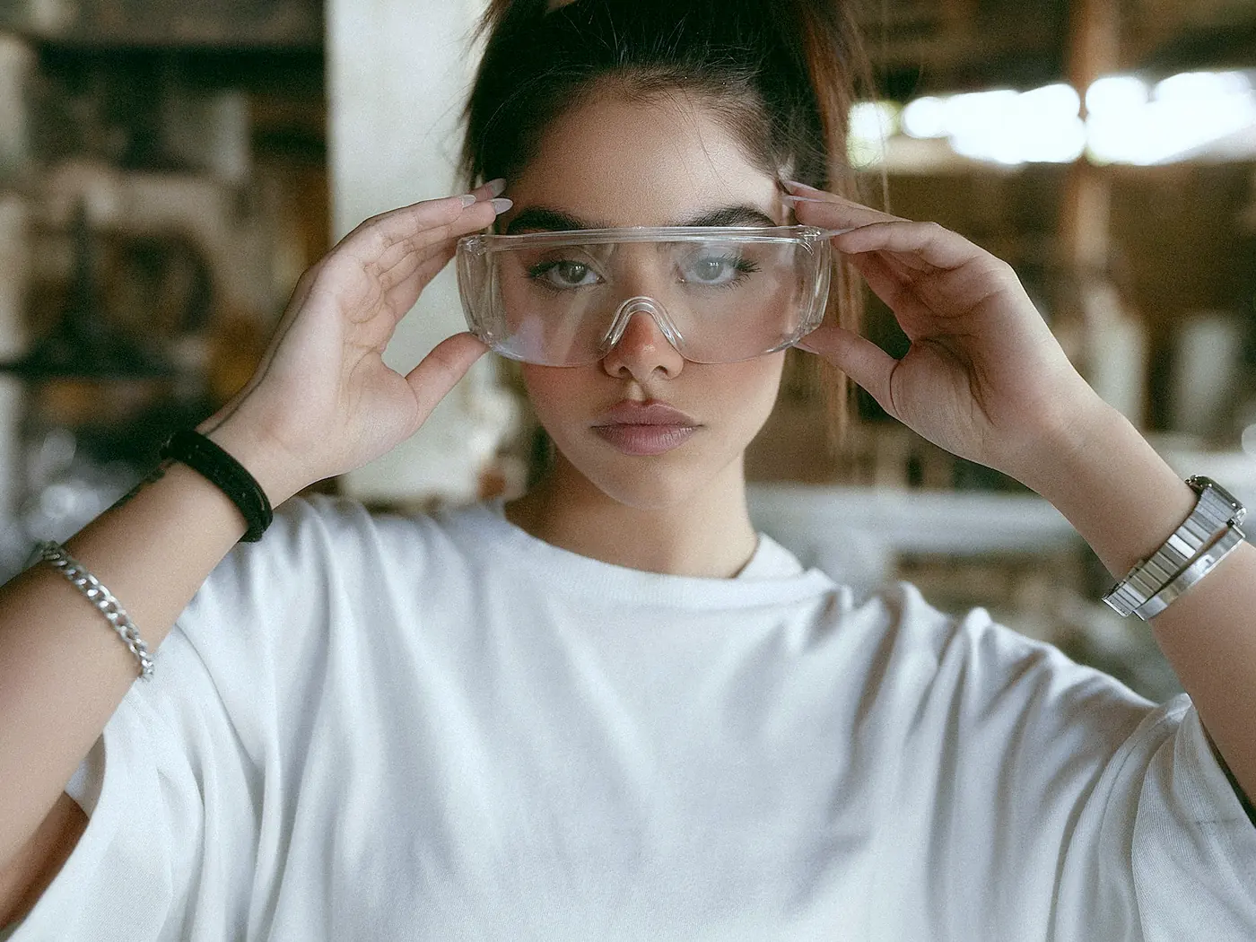 A worker fitting clear wraparound safety glasses in a workshop
